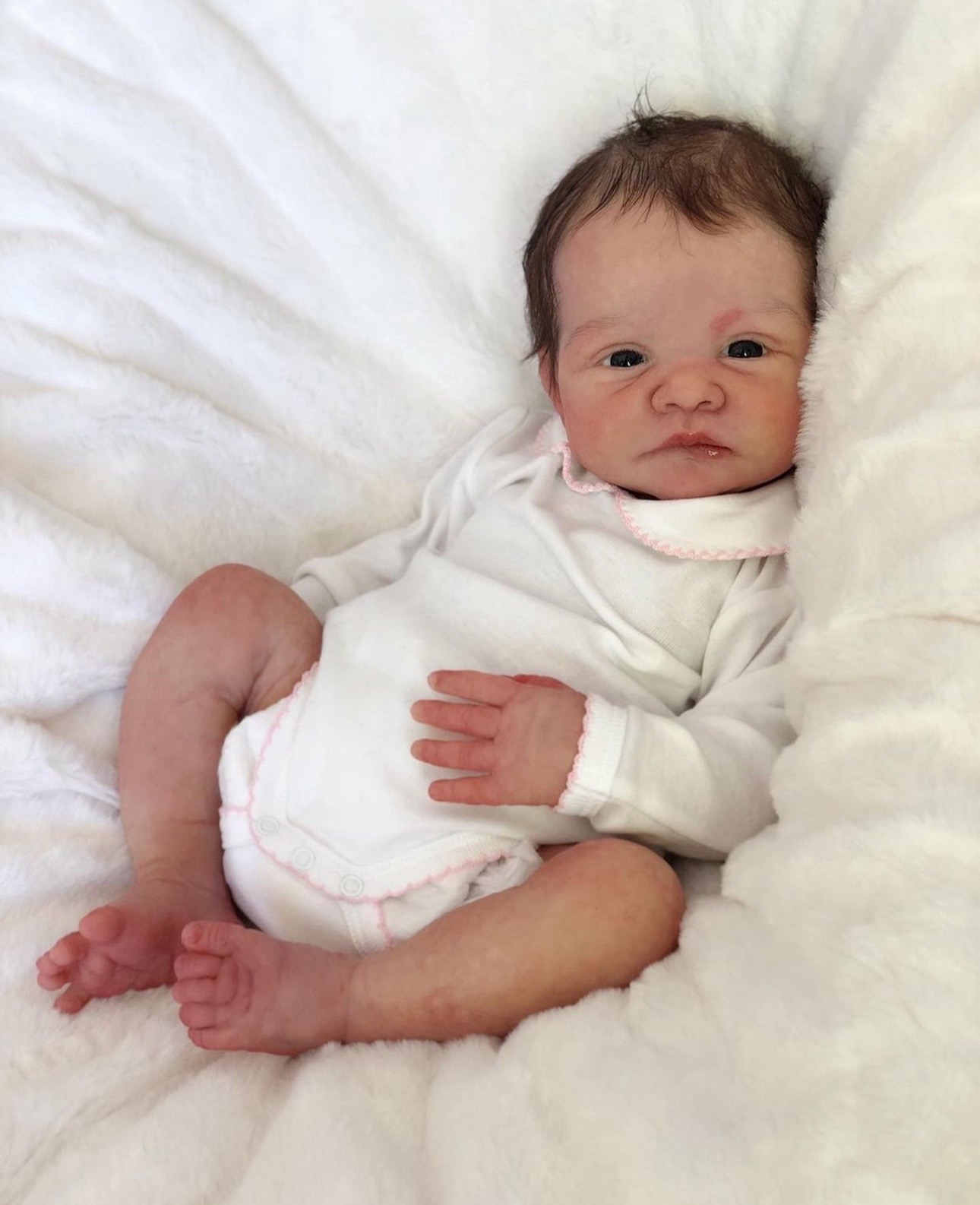 Baby Avery, an 18-inch realistic full body silicone reborn baby doll with opened eyes and dark hair by Reborn Heaven.